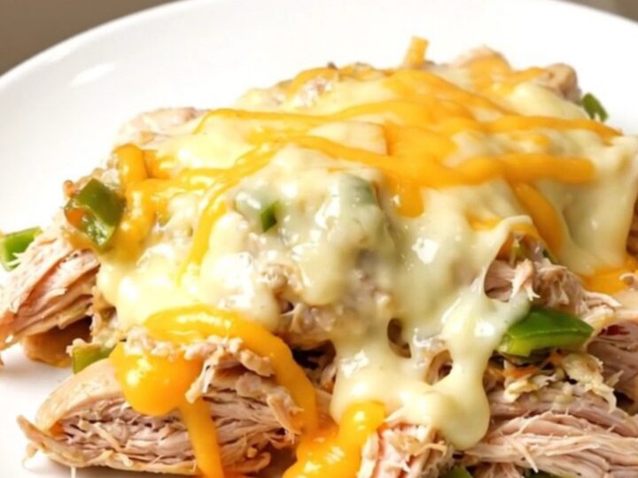 Close up of creamy shredded chicken with poblano peppers and melted pepper jack cheese in a slow cooker.