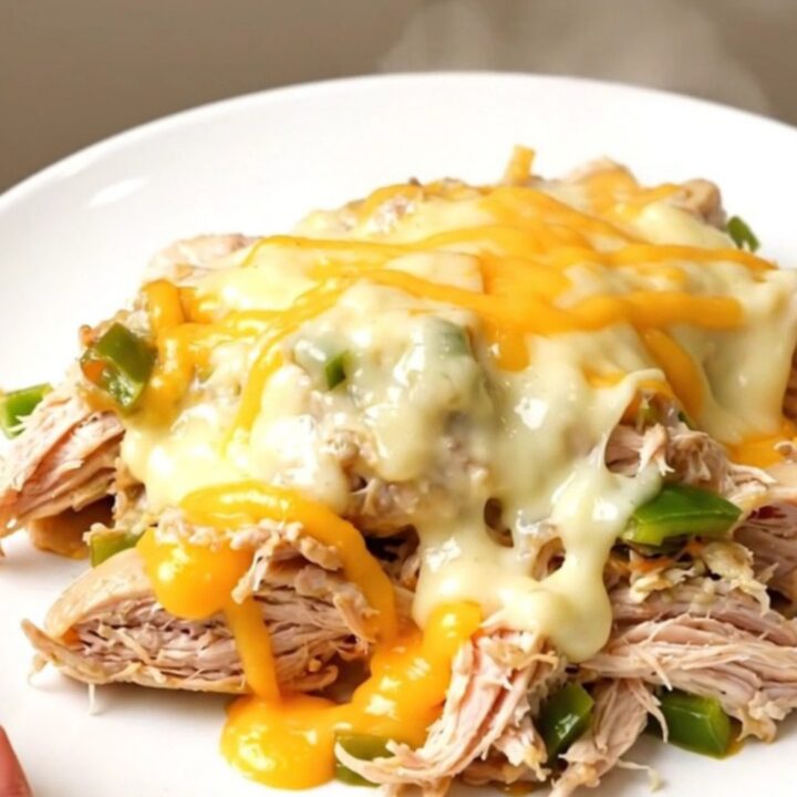 Close up of creamy shredded chicken with poblano peppers and melted pepper jack cheese in a slow cooker.