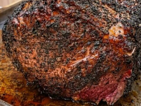 A magnificent prime rib roast with four frenched bones and a deep, crispy garlic-herb butter crust.