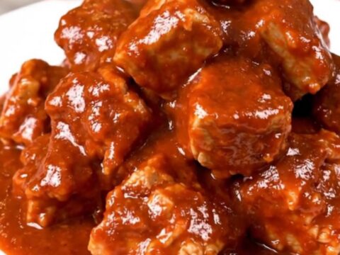 Slow cooker filled with tender, cubed pork shoulder in a rich, red chile sauce.