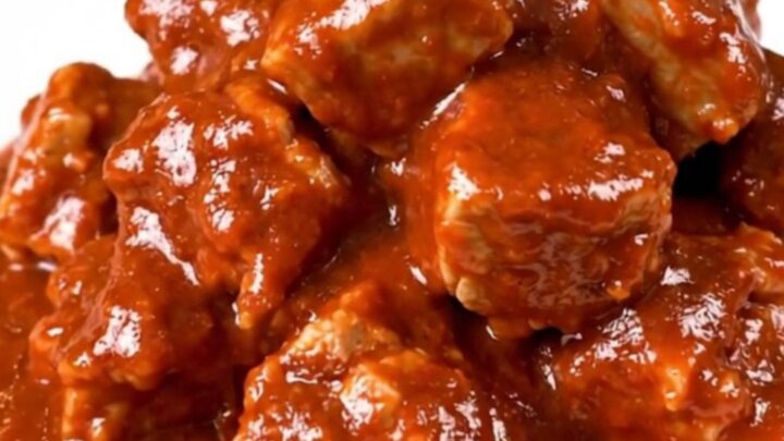 Slow cooker filled with tender, cubed pork shoulder in a rich, red chile sauce.