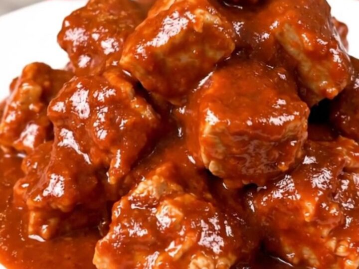 Slow cooker filled with tender, cubed pork shoulder in a rich, red chile sauce.