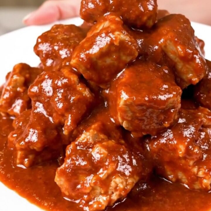 Slow cooker filled with tender, cubed pork shoulder in a rich, red chile sauce.