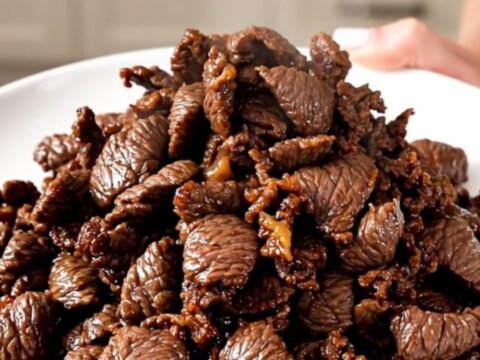 A close-up view of tender, glossy Korean beef bulgogi served on a white plate.