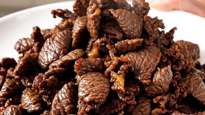 A close-up view of tender, glossy Korean beef bulgogi served on a white plate.