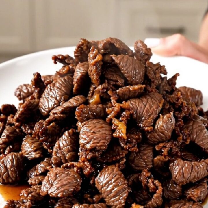 A close-up view of tender, glossy Korean beef bulgogi served on a white plate.