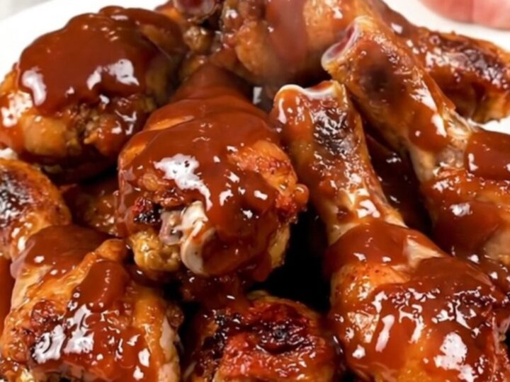 A top-down view of cooked barbecue ranch chicken drumsticks on a white plate.