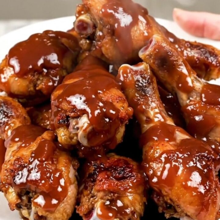 A top-down view of cooked barbecue ranch chicken drumsticks on a white plate.