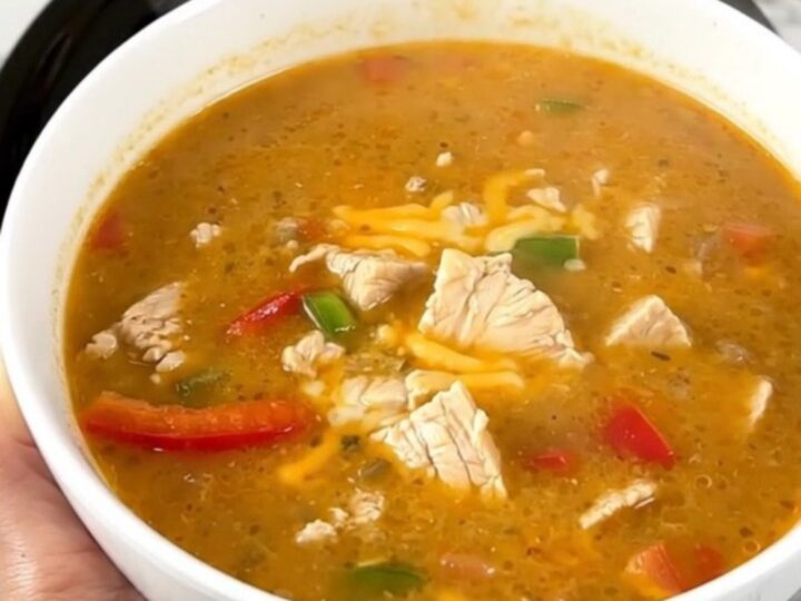 A steaming bowl of creamy chicken fajita soup garnished with fresh cilantro on a white countertop.