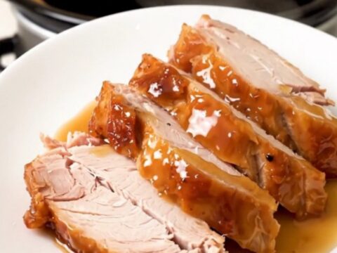 A close-up of sliced, glossy, fully cooked honey soy turkey breast on a white plate.