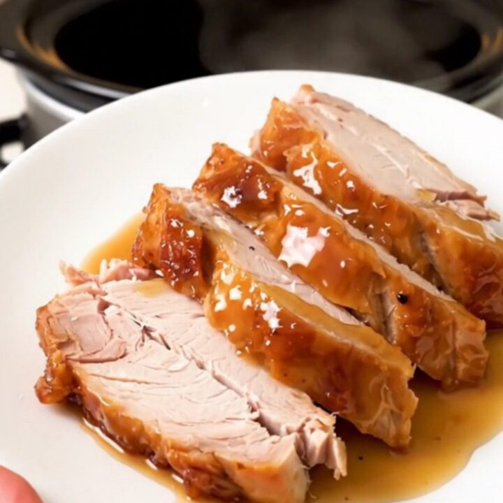 A close-up of sliced, glossy, fully cooked honey soy turkey breast on a white plate.