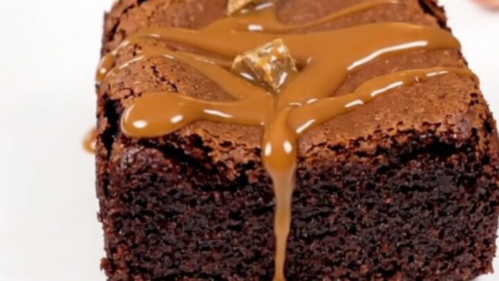 A top-down view of a black slow cooker filled with rich, glossy chocolate brownie batter topped with chocolate chunks