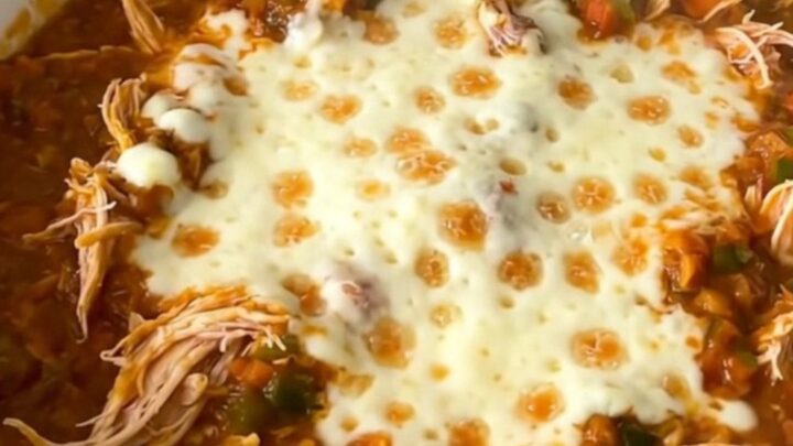 A close-up of a bowl filled with shredded chicken chili topped with melted mozzarella cheese.