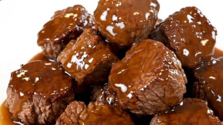 A close-up of glistening honey garlic steak bites served on a white plate, showing the rich glaze.