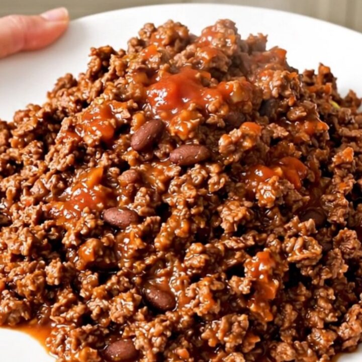 A steaming, glossy portion of ground beef burrito filling served on a plain white plate.