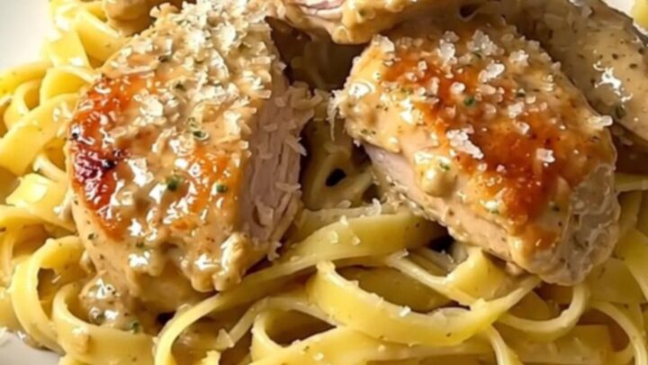 Creamy lemon parmesan chicken served over pasta on a white plate.
