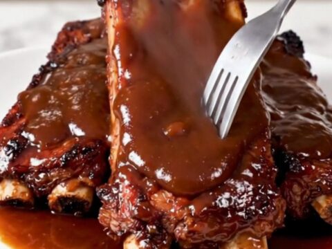 A close-up of glossy, fork-tender country-style ribs served on a white plate.