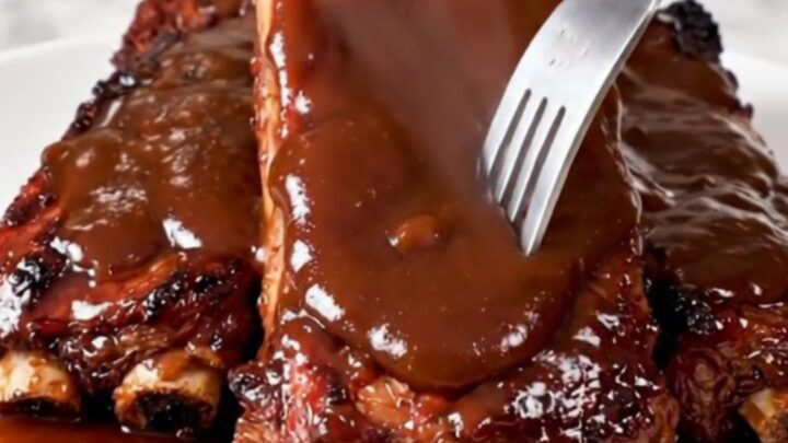 A close-up of glossy, fork-tender country-style ribs served on a white plate.