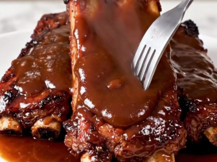 A close-up of glossy, fork-tender country-style ribs served on a white plate.
