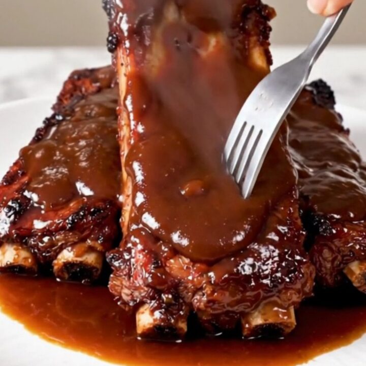 A close-up of glossy, fork-tender country-style ribs served on a white plate.