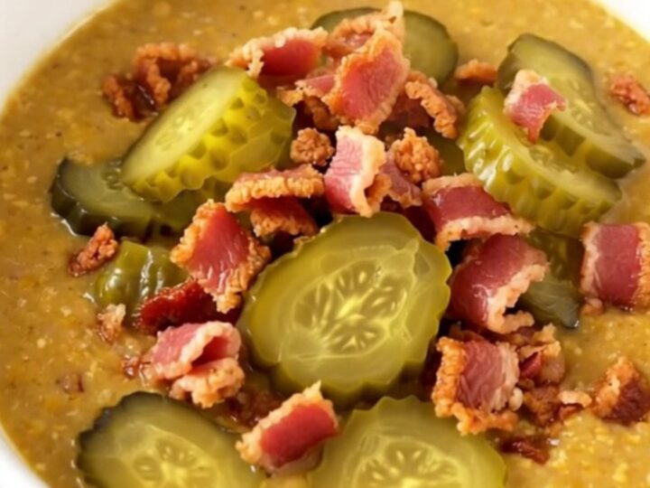 A steaming bowl of creamy cheeseburger soup topped with crispy bacon and diced pickles.