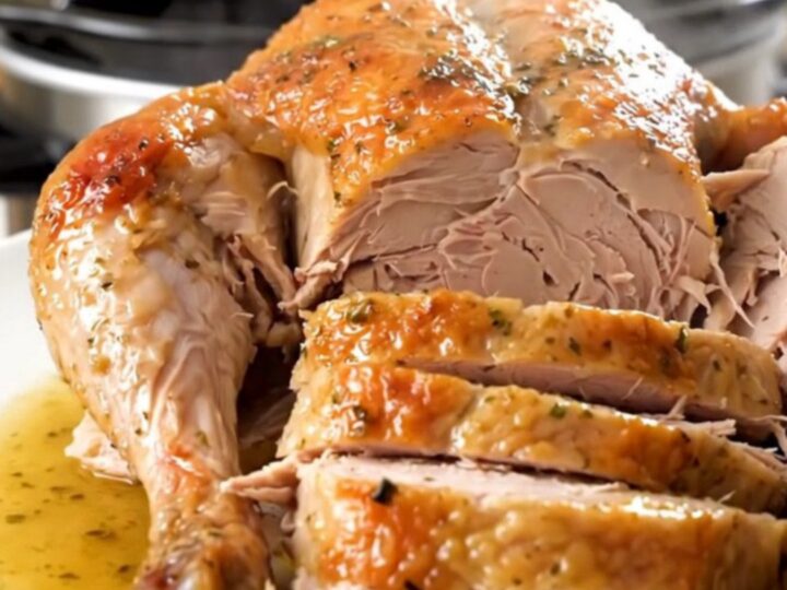A beautifully cooked, glistening turkey breast seasoned with fresh rosemary on a white plate.