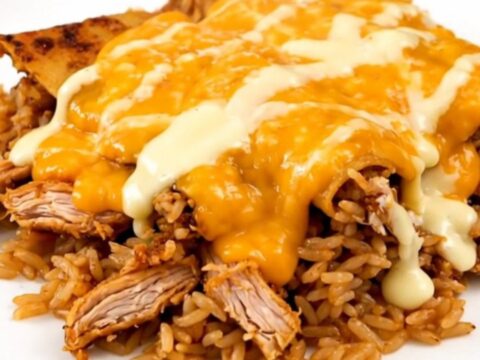 A steaming plate of shredded cheesy enchilada chicken and rice served in a white bowl.