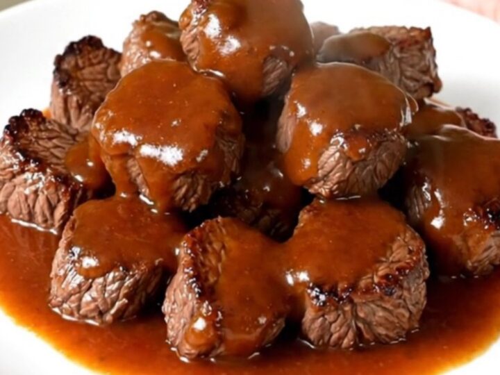 A top-down view of raw steak cubes, red bell peppers, and chili sauce being added to a slow cooker.