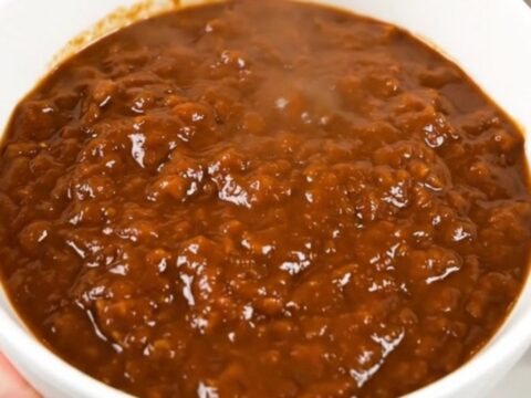 A top-down view of a black slow cooker filled with hearty beef and kidney bean chili.