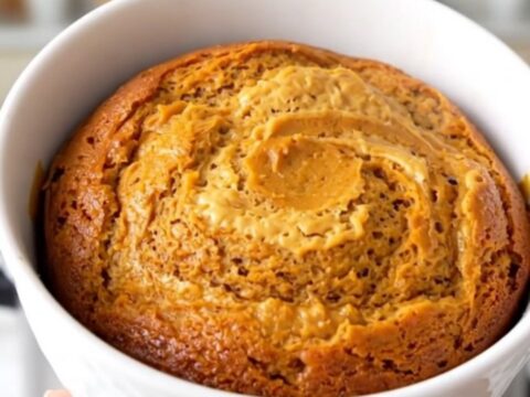 A close-up view of the finished pumpkin cream cheese swirl cake in a white bowl showing the moist texture.