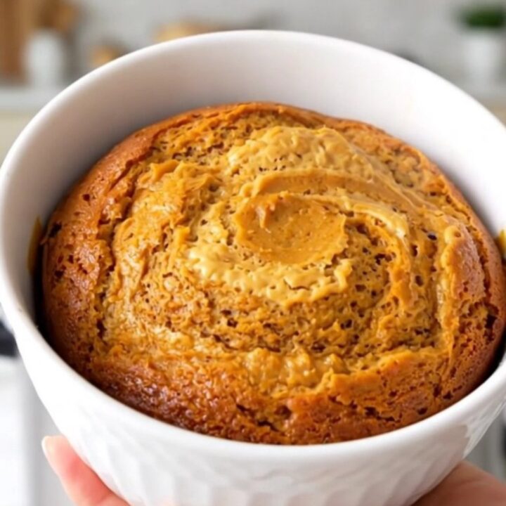 A close-up view of the finished pumpkin cream cheese swirl cake in a white bowl showing the moist texture.