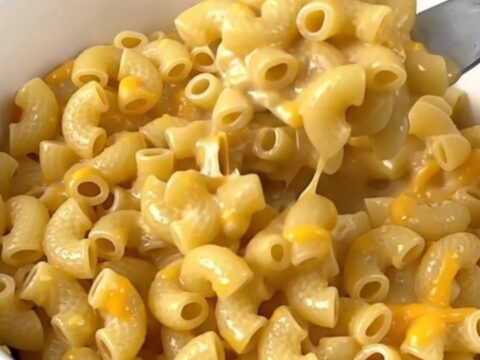 A close-up of creamy macaroni in a white bowl with visible jalapeno pieces.
