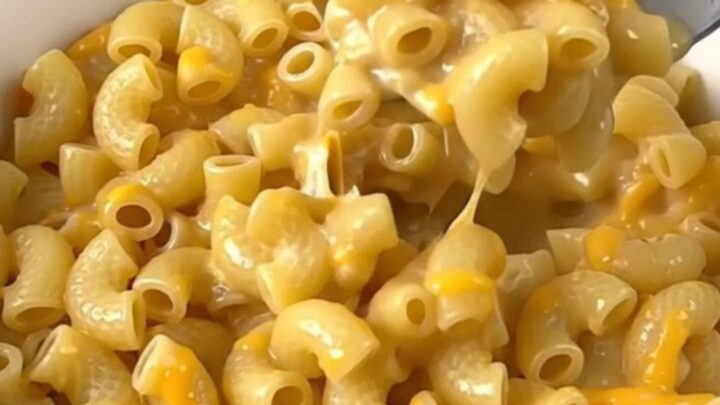 A close-up of creamy macaroni in a white bowl with visible jalapeno pieces.
