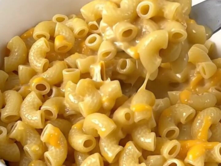 A close-up of creamy macaroni in a white bowl with visible jalapeno pieces.