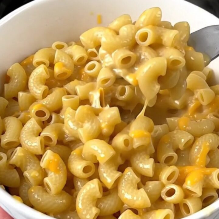 A close-up of creamy macaroni in a white bowl with visible jalapeno pieces.