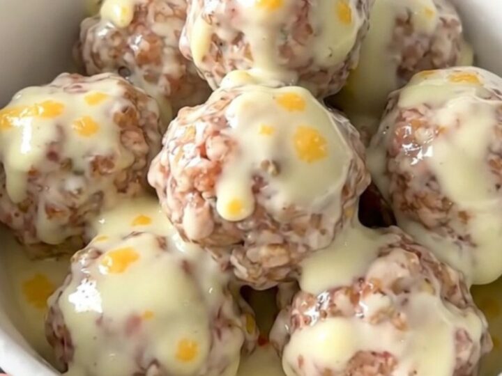 A white bowl filled with creamy queso blanco meatballs garnished with green chiles.