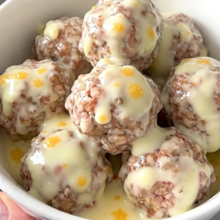 A white bowl filled with creamy queso blanco meatballs garnished with green chiles.
