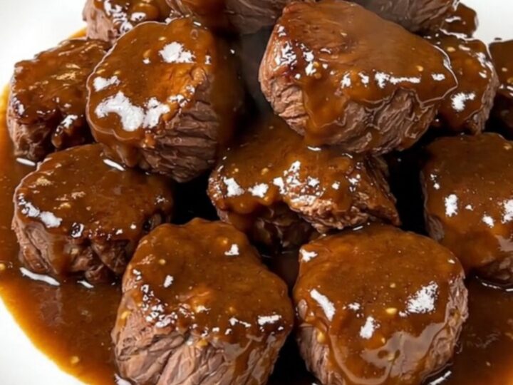 A close-up of tender, glossy brown sugar Dijon steak bites served on a white plate.