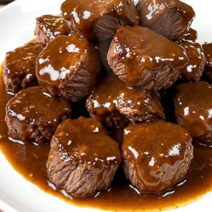 A close-up of tender, glossy brown sugar Dijon steak bites served on a white plate.