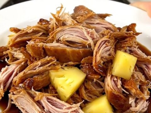Slow-cooked shredded teriyaki turkey served with pineapple chunks on a white plate.