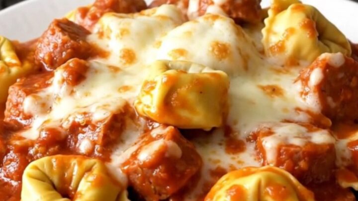 A close-up of a bowl of slow-cooked Italian sausage and cheese tortellini topped with melted mozzarella.