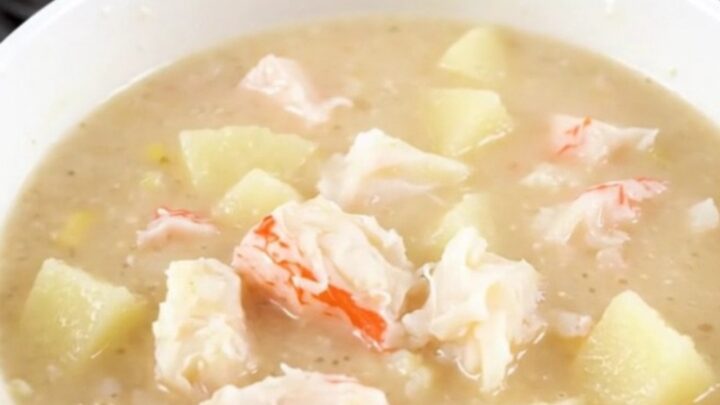 A steaming bowl of creamy crab chowder with visible pieces of potato and crab meat.