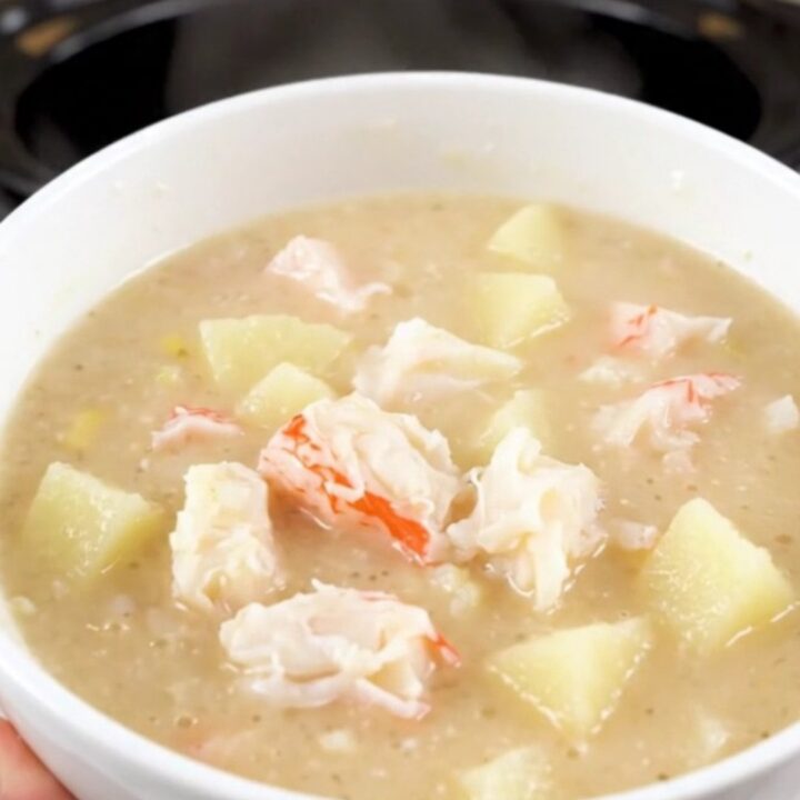 A steaming bowl of creamy crab chowder with visible pieces of potato and crab meat.