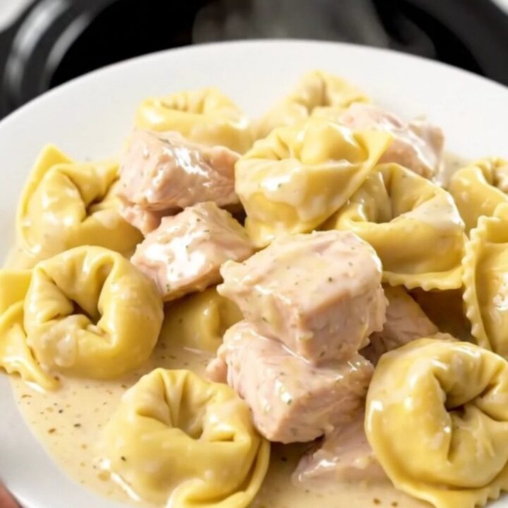 A steaming, creamy bowl of slow cooker chicken and cheese tortellini in a rich alfredo sauce.