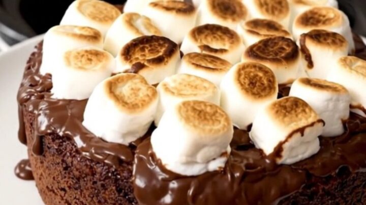 A top-down view of a black slow cooker filled with a freshly prepared chocolate s'mores dump cake.