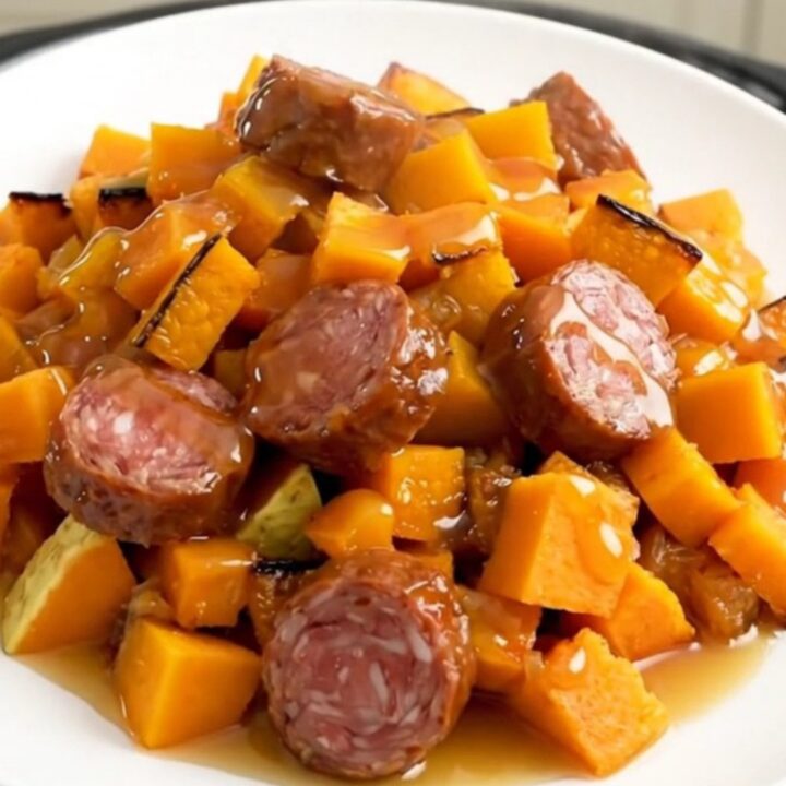 A finished slow cooker smoked sausage and butternut squash bake served on a white plate.