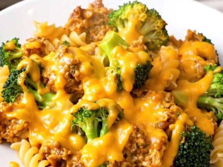 A steaming bowl of rotini pasta with broccoli florets coated in a thick, creamy cheddar cheese sauce.