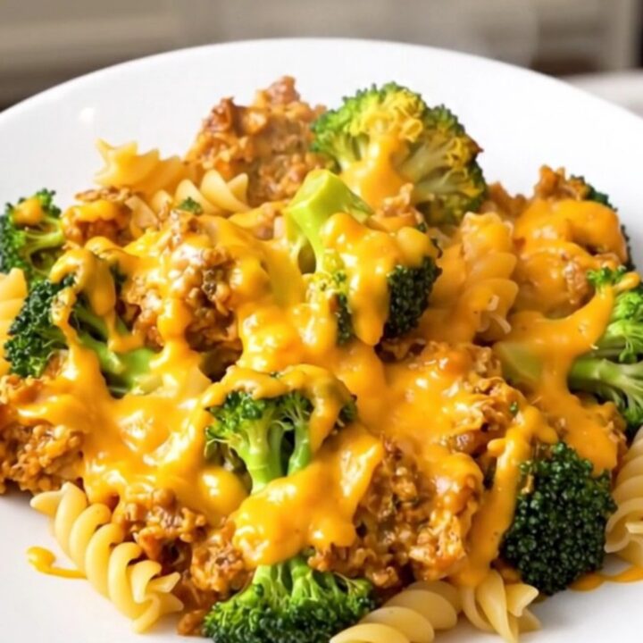 A steaming bowl of rotini pasta with broccoli florets coated in a thick, creamy cheddar cheese sauce.