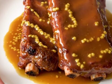 A plate of glossy, golden-brown honey mustard country-style ribs served on a clean white plate.