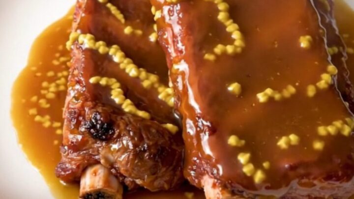 A plate of glossy, golden-brown honey mustard country-style ribs served on a clean white plate.